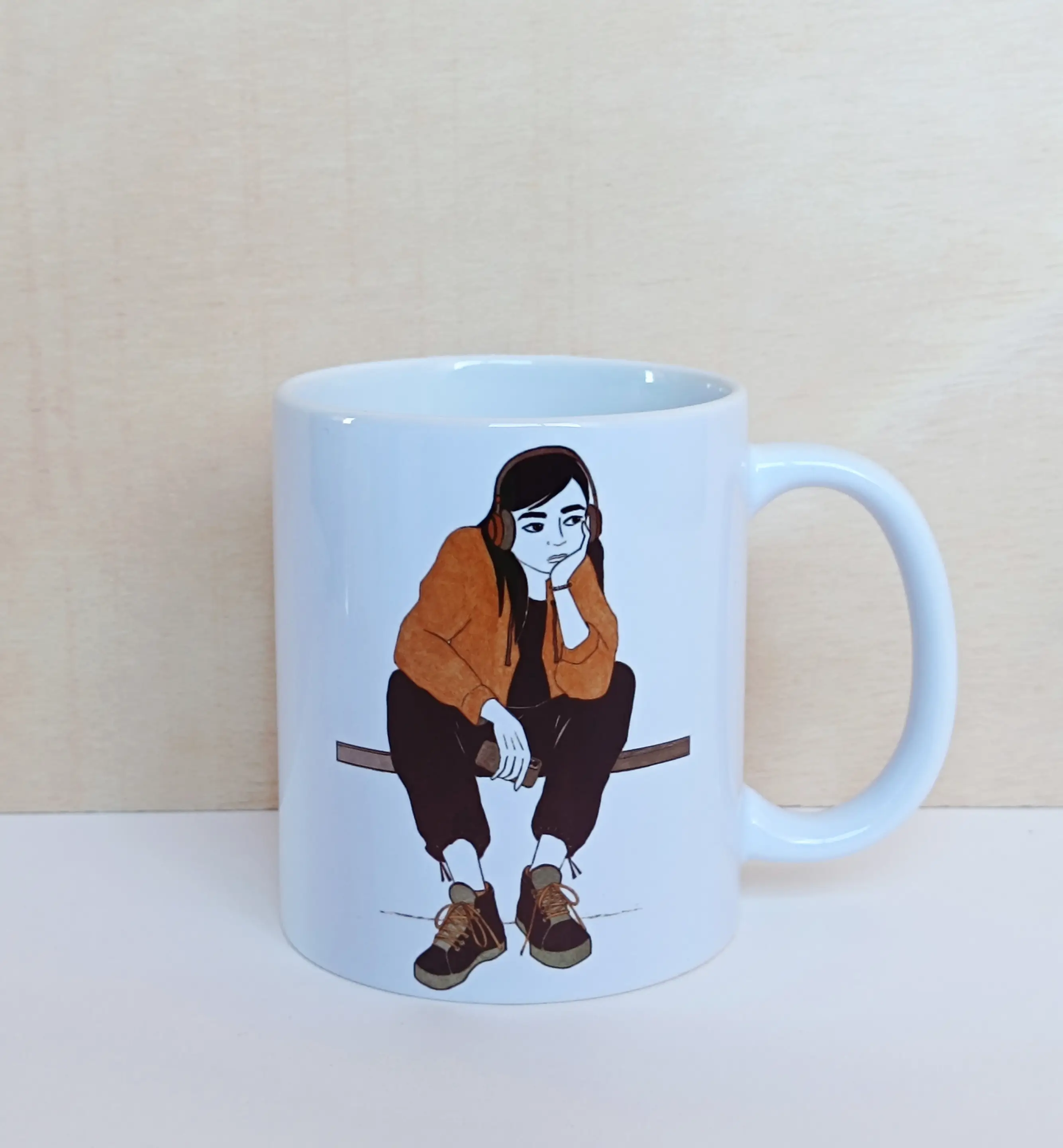 taza de cerámica blanca con ilustración a tinta de chica sentada con auriculares