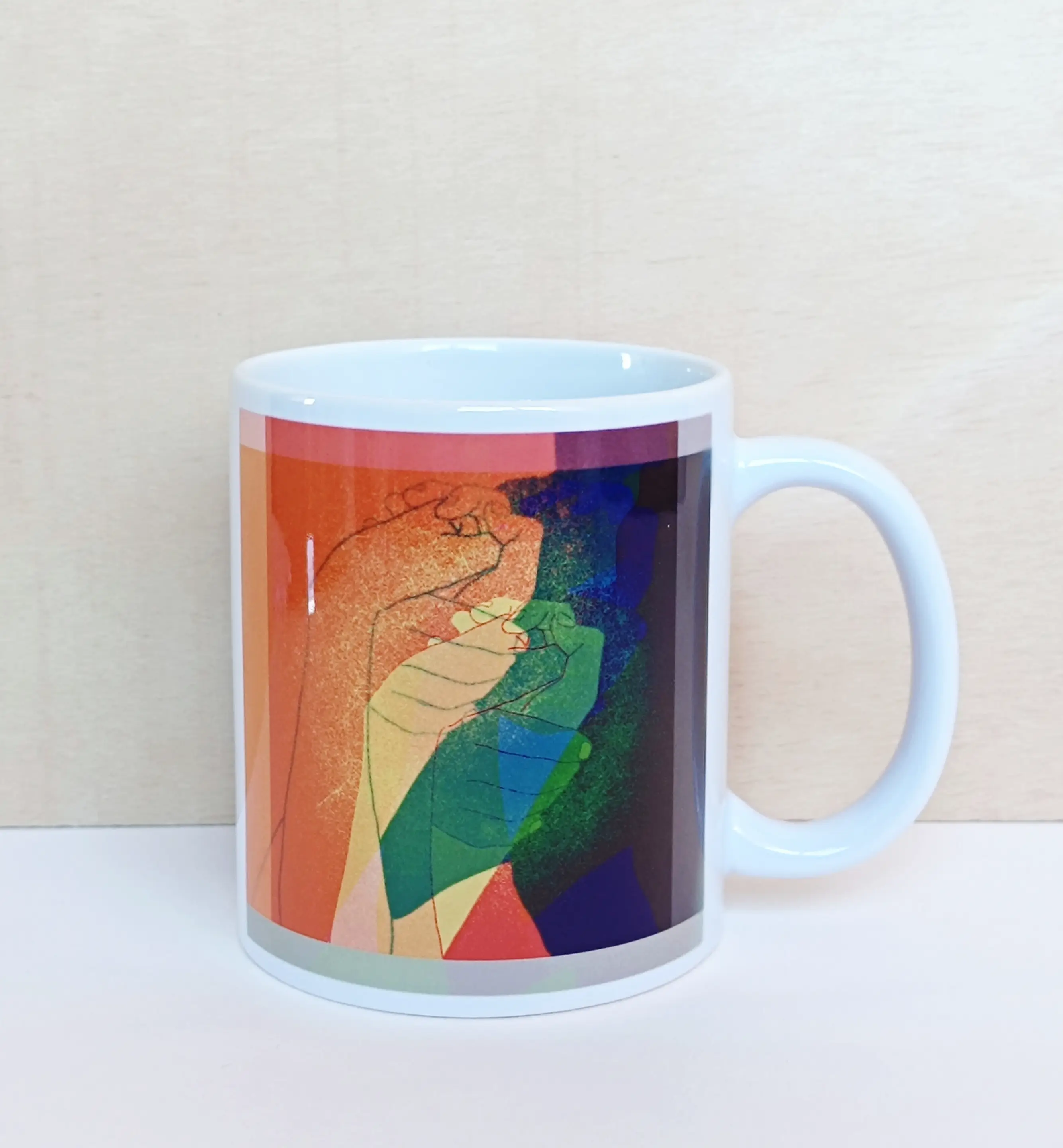taza de cerámica blanca con ilustración de colores que representa unas manos entrelazadas