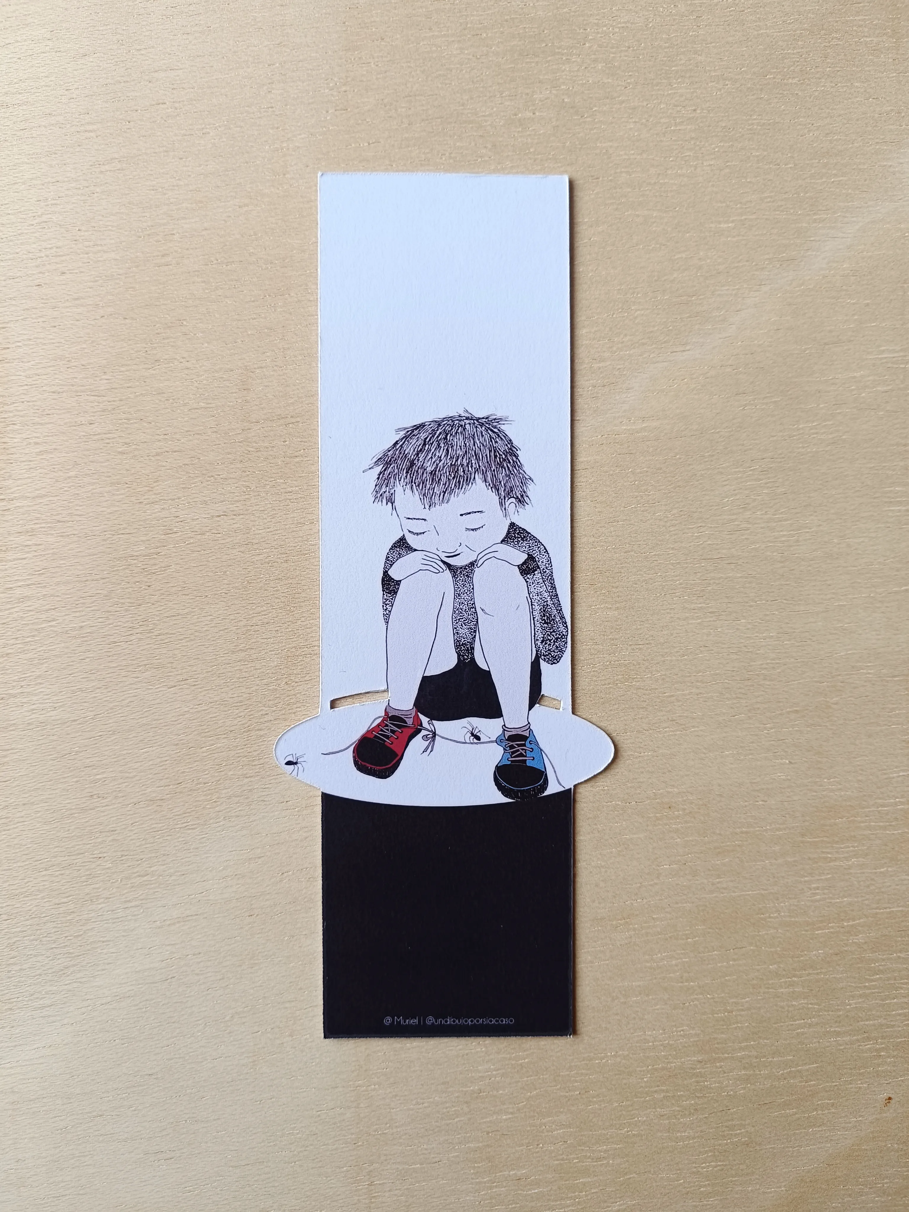 Marcapáginas de libro, con ilustración que representa un niño sentado en el suelo mirando unas arañas y fondo blanco y negro.