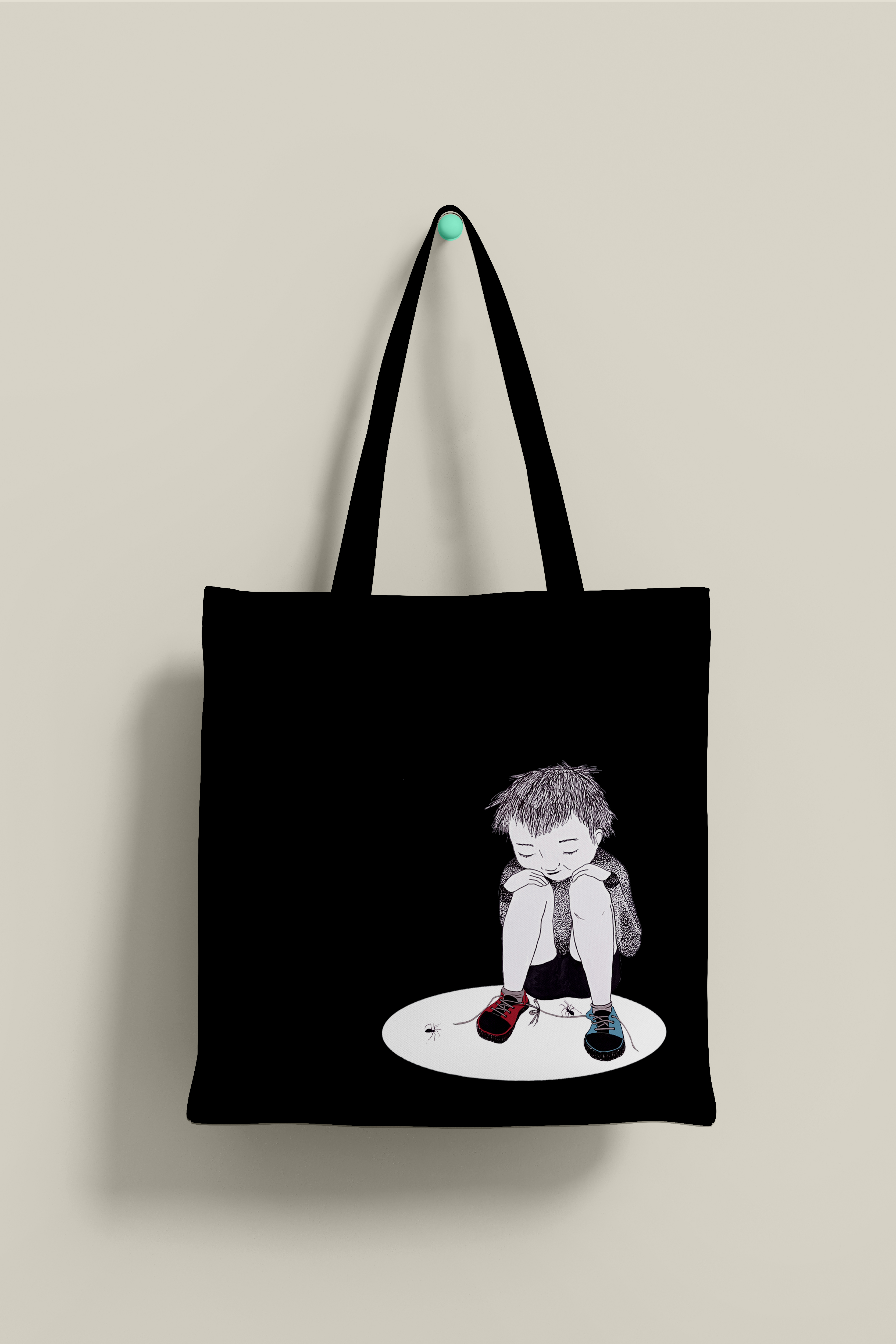 Bolsa de tela, de color negro, con ilustración de niño sentado en el suelo con dos arañas.