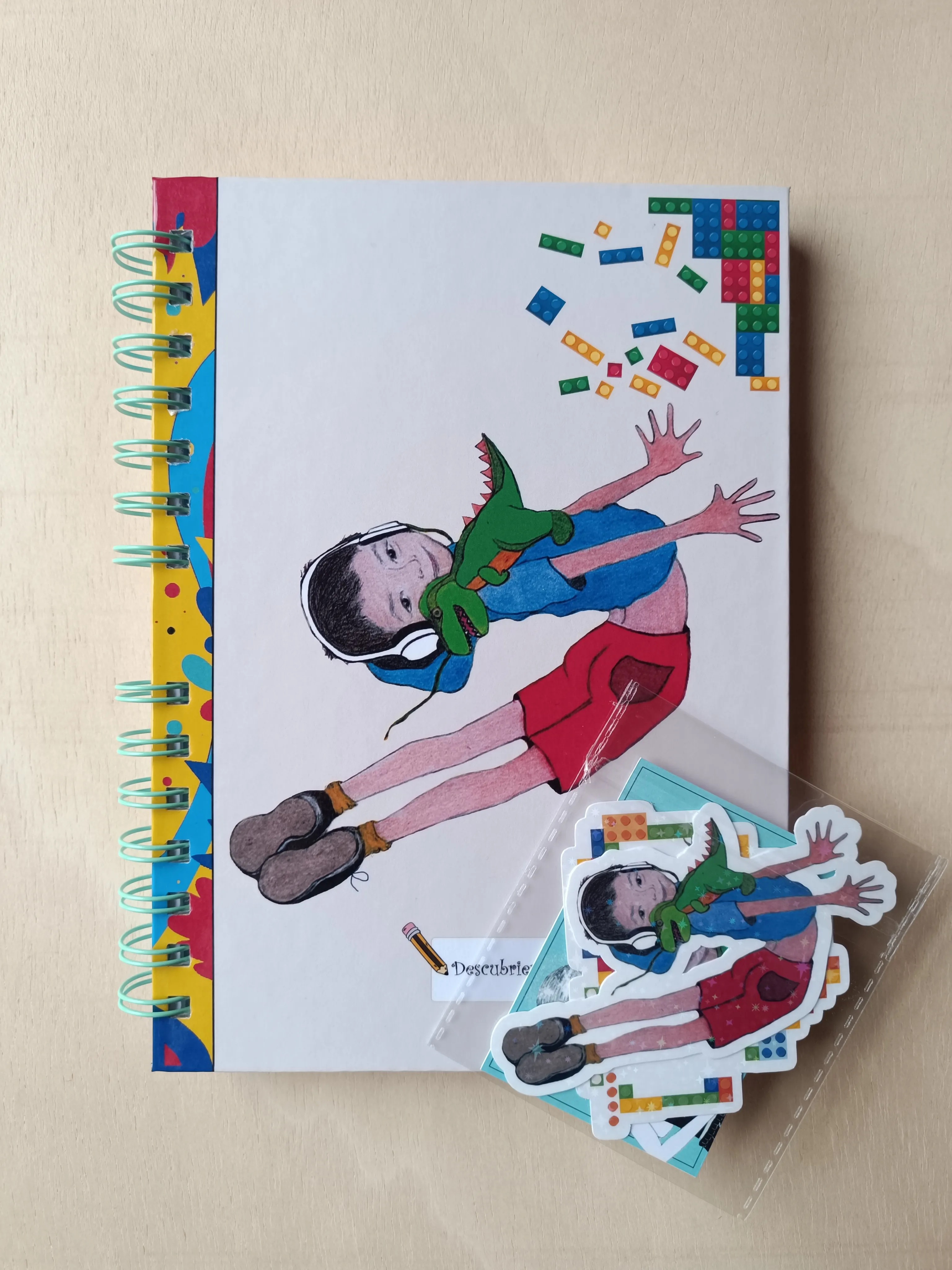 Foto de la portada de una libreta personalizada con un dibujo que representa a un niño saltando, con auriculares y un peluche con forma de dinosaurio.